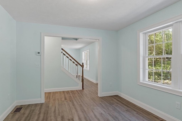 unfurnished room with visible vents, plenty of natural light, and wood finished floors