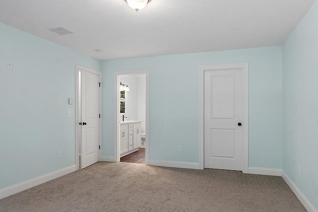 unfurnished bedroom with baseboards, connected bathroom, visible vents, and carpet