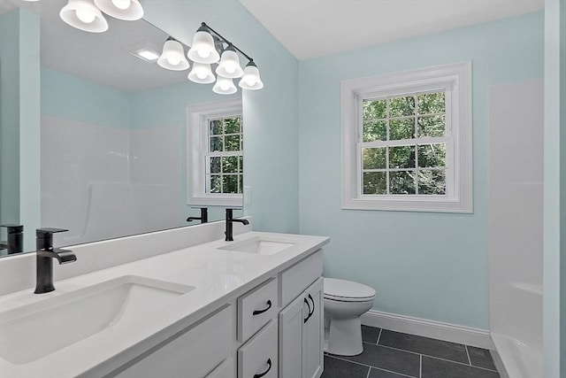 bathroom with a sink, double vanity, toilet, and tile patterned floors