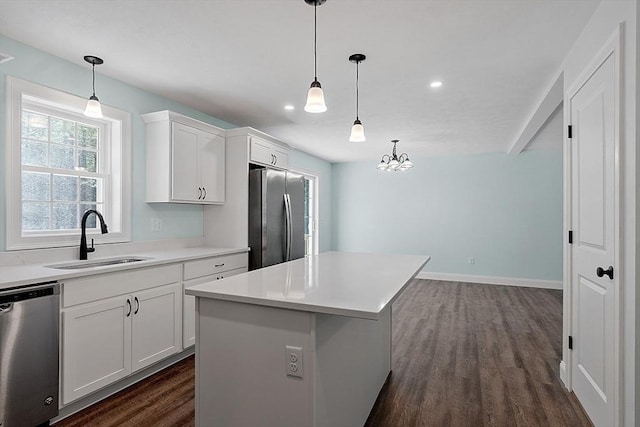 kitchen featuring dark wood finished floors, a sink, a kitchen island, stainless steel appliances, and white cabinets