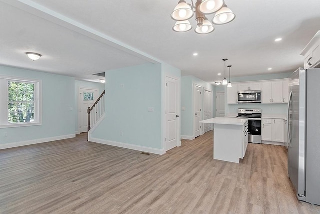 kitchen with stainless steel appliances, baseboards, a notable chandelier, a kitchen island, and light wood-style floors