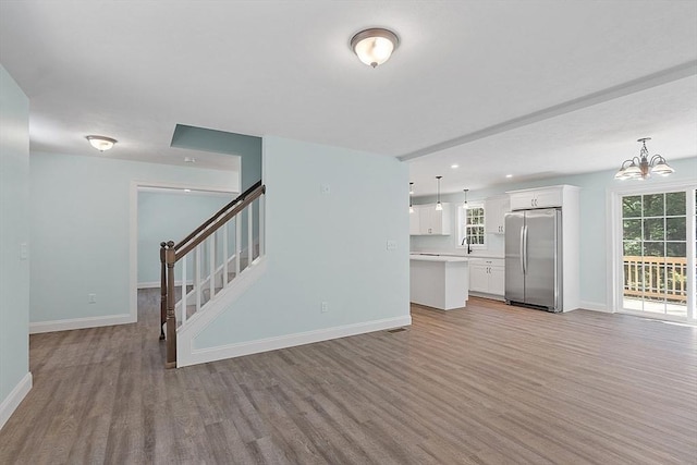 unfurnished living room with recessed lighting, stairway, baseboards, a chandelier, and light wood-style floors