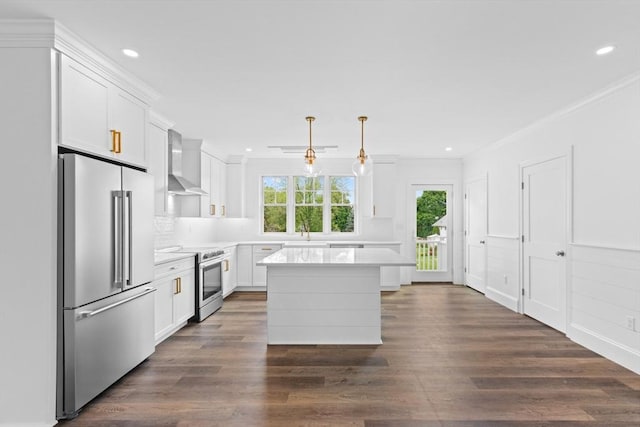 kitchen featuring pendant lighting, wall chimney exhaust hood, white cabinetry, and appliances with stainless steel finishes