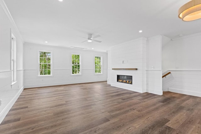 unfurnished living room with a large fireplace, ornamental molding, and dark wood-type flooring