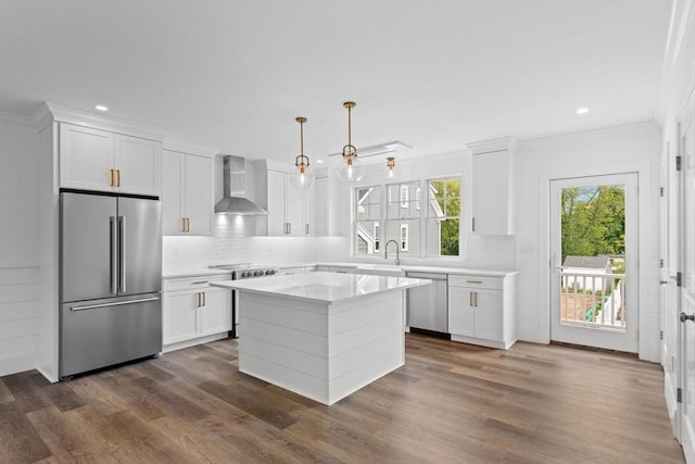 kitchen with white cabinets, a center island, stainless steel appliances, and wall chimney exhaust hood