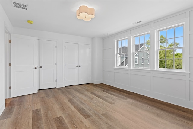 unfurnished bedroom featuring multiple closets and light hardwood / wood-style floors