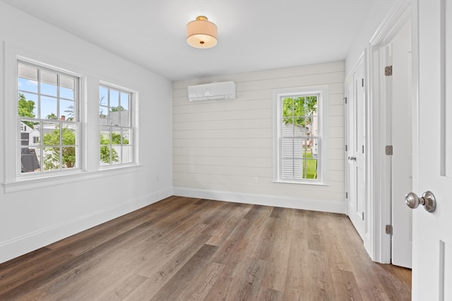 empty room with a wall mounted air conditioner and hardwood / wood-style flooring