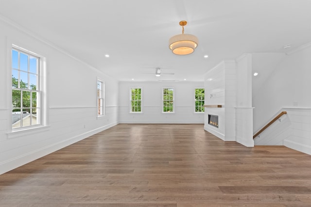 unfurnished living room featuring a fireplace, ornamental molding, a healthy amount of sunlight, and wood-type flooring