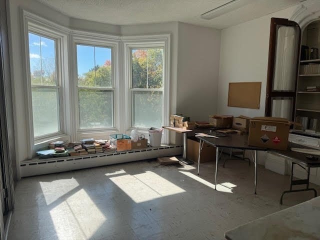 miscellaneous room with a baseboard radiator, plenty of natural light, and a textured ceiling