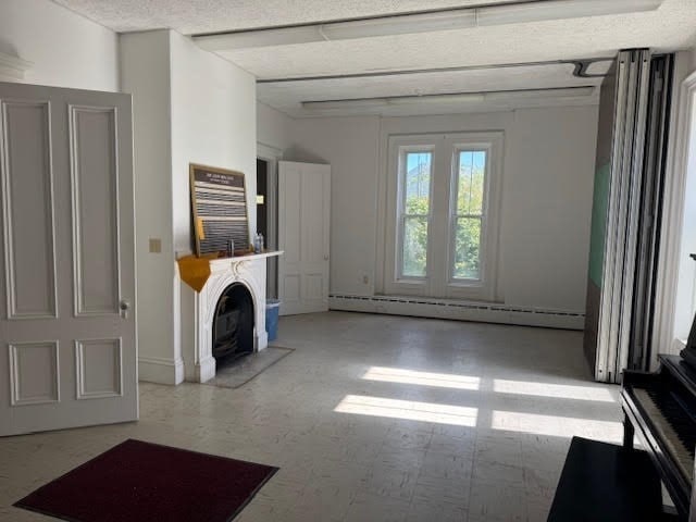 unfurnished living room with a baseboard radiator and a textured ceiling