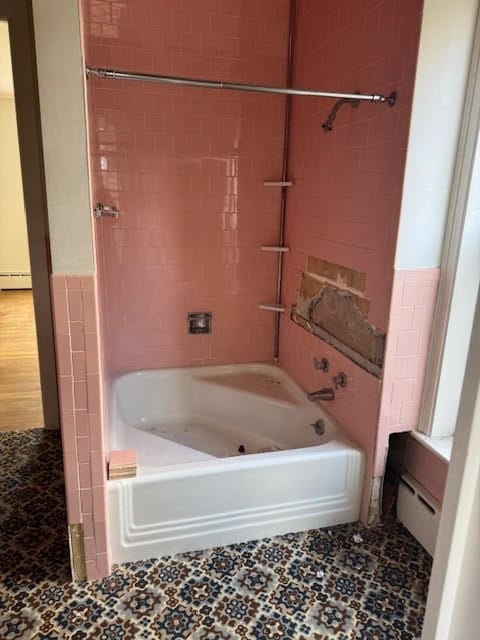 bathroom with tile walls, tiled shower / bath, and a baseboard radiator