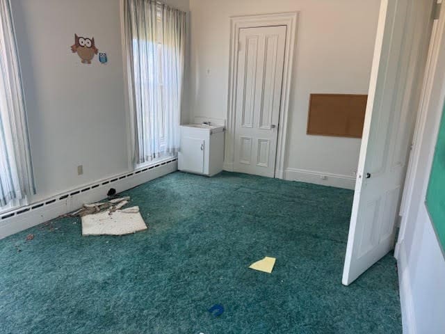 interior space featuring dark carpet, baseboard heating, and a wealth of natural light