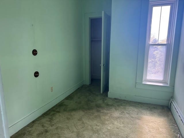 carpeted empty room featuring a baseboard radiator and a healthy amount of sunlight