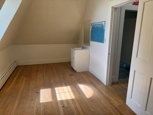 bonus room featuring baseboard heating, light hardwood / wood-style flooring, and lofted ceiling with skylight