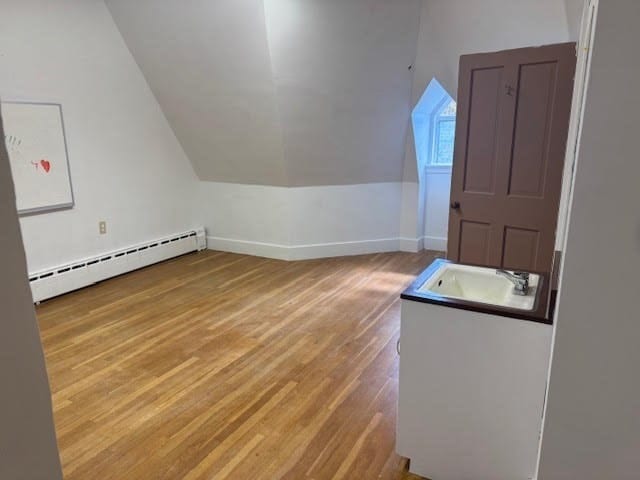 bonus room with wood-type flooring, vaulted ceiling, sink, and a baseboard heating unit