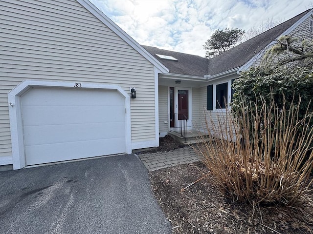 property entrance featuring a garage, aphalt driveway, and a shingled roof