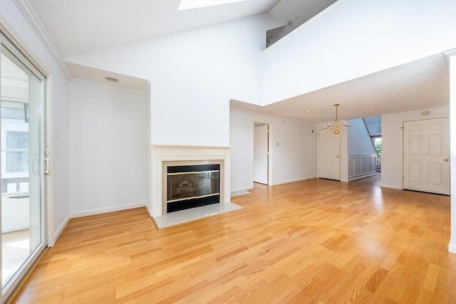 unfurnished living room featuring baseboards, a fireplace with flush hearth, ornamental molding, light wood-style floors, and a chandelier