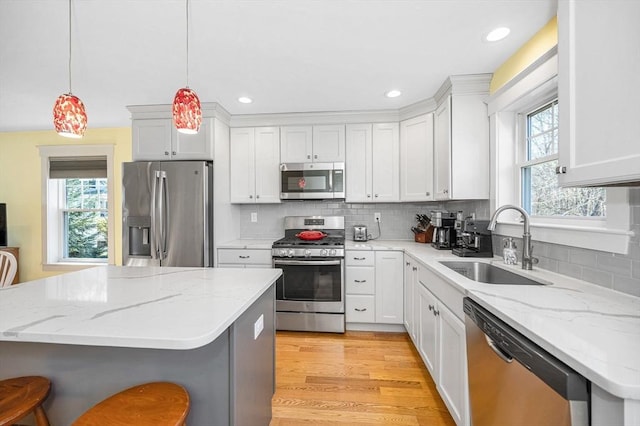 kitchen featuring a breakfast bar area, decorative backsplash, light wood-style floors, stainless steel appliances, and a sink