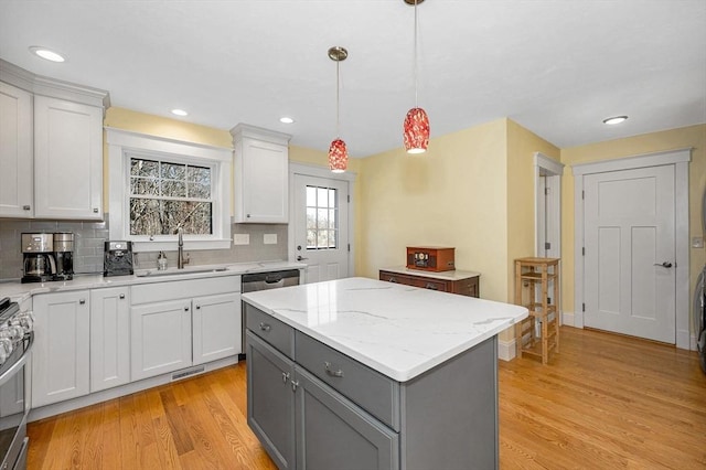 kitchen with light wood-type flooring, a sink, gray cabinetry, white cabinets, and tasteful backsplash