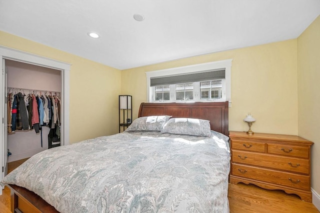 bedroom with a spacious closet, recessed lighting, wood finished floors, and a closet