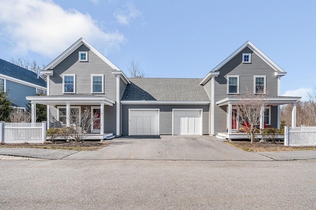 traditional-style home featuring aphalt driveway, an attached garage, fence, and covered porch