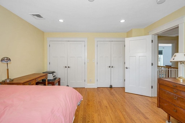 bedroom featuring recessed lighting, visible vents, two closets, and light wood-style flooring