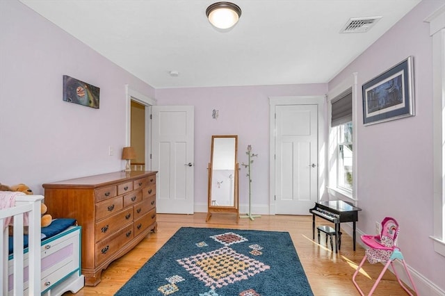 bedroom with light wood-style flooring, baseboards, and visible vents