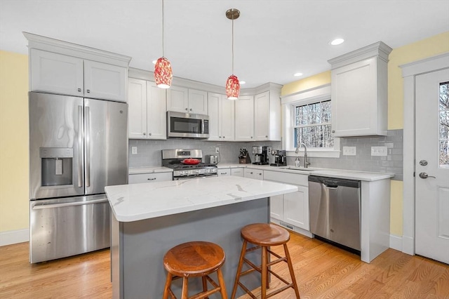 kitchen featuring a kitchen island, stainless steel appliances, light wood-type flooring, and a sink