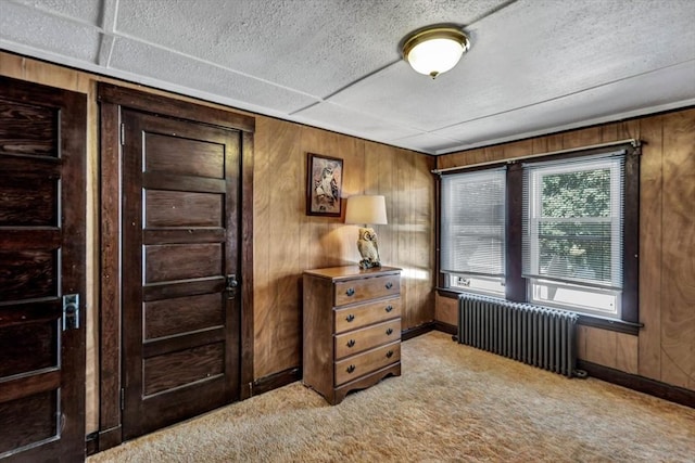 interior space with radiator, wood walls, and light carpet