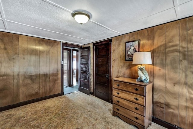 interior space featuring a textured ceiling, carpet flooring, and wooden walls