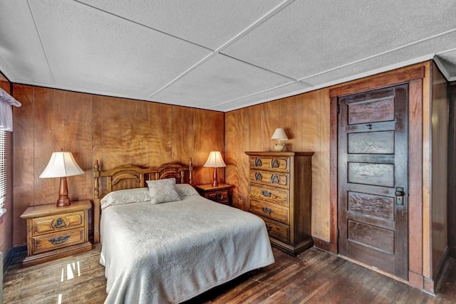 bedroom featuring dark wood-type flooring and wood walls