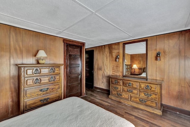 bedroom with wooden walls, baseboards, and dark wood-type flooring