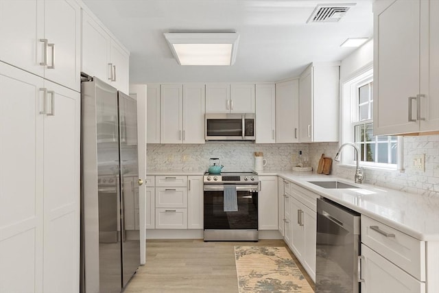 kitchen with visible vents, a sink, light countertops, light wood finished floors, and stainless steel appliances