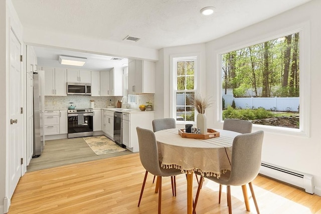 kitchen featuring light wood-style floors, baseboard heating, stainless steel appliances, and visible vents