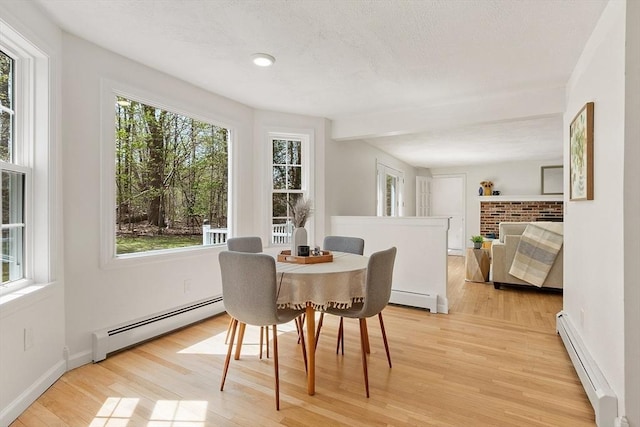 dining room with light wood-type flooring, a baseboard radiator, baseboards, and a baseboard heating unit
