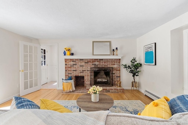 living area with a brick fireplace, baseboards, baseboard heating, and wood finished floors