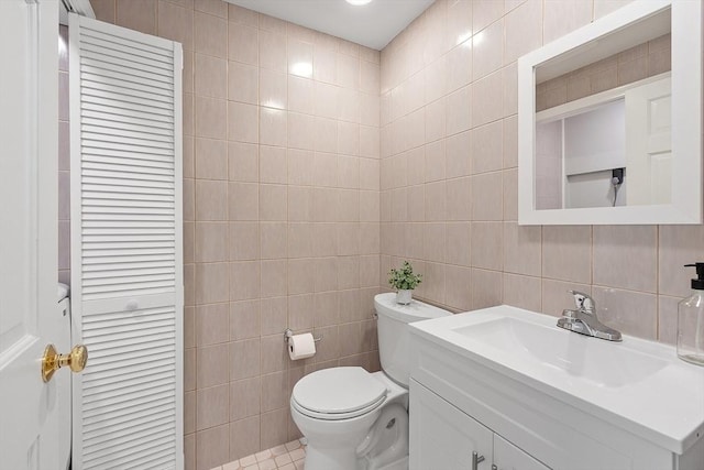 half bathroom with toilet, tile walls, a closet, and vanity