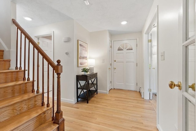 foyer entrance with baseboards, stairway, light wood-type flooring, recessed lighting, and a textured ceiling