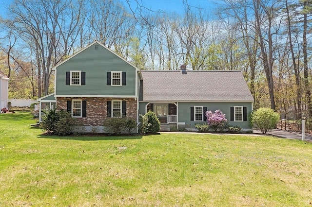 split level home with roof with shingles, a chimney, a front yard, and brick siding