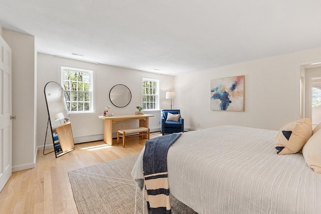 bedroom featuring baseboards, visible vents, light wood finished floors, and a baseboard radiator