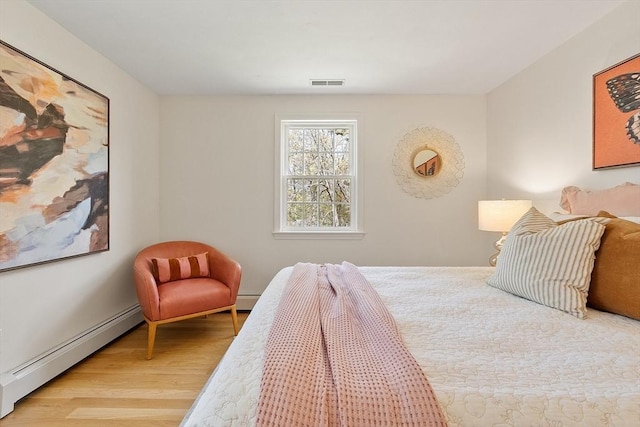 bedroom with visible vents, a baseboard radiator, a baseboard heating unit, and wood finished floors