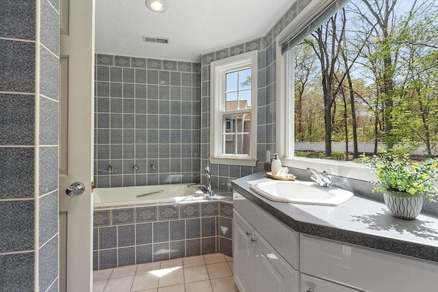 full bath with tile patterned floors, vanity, a garden tub, and visible vents
