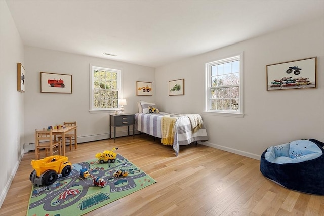 bedroom featuring baseboards, multiple windows, and light wood finished floors
