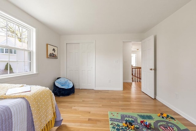 bedroom with a closet, baseboards, and light wood-style floors