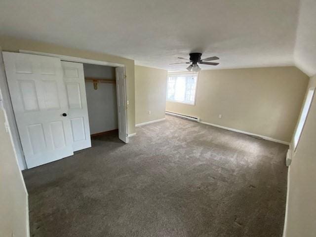 unfurnished bedroom featuring baseboard heating, ceiling fan, dark carpet, and a closet