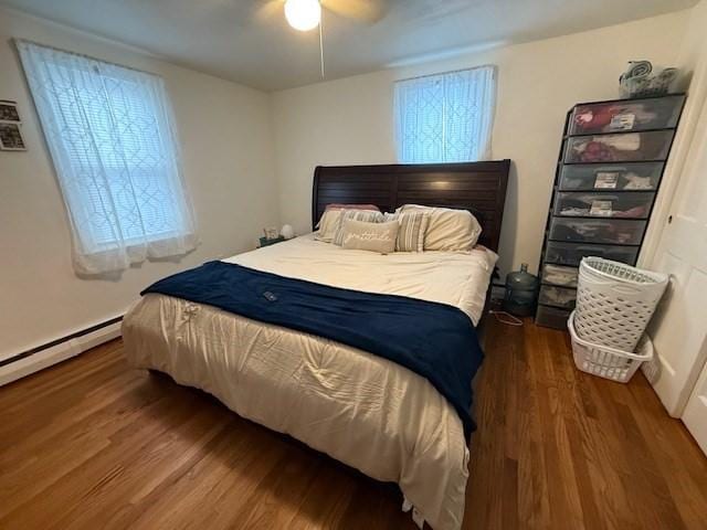 bedroom featuring multiple windows, a baseboard radiator, hardwood / wood-style floors, and ceiling fan