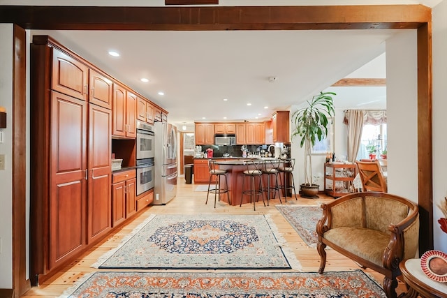 kitchen with stainless steel appliances, backsplash, sink, a kitchen bar, and light hardwood / wood-style floors