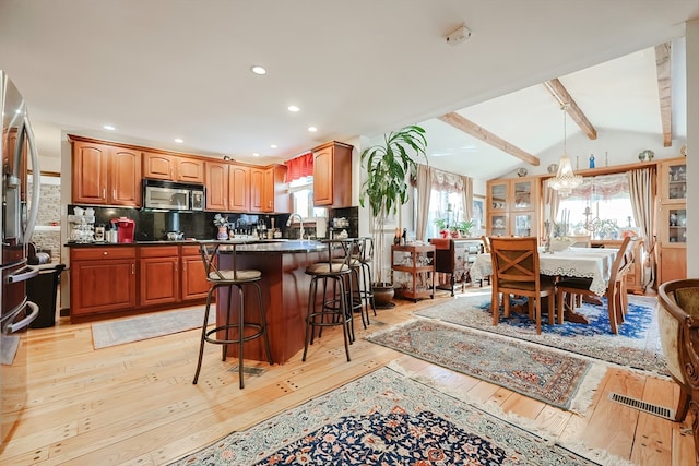 kitchen featuring tasteful backsplash, vaulted ceiling with beams, a kitchen breakfast bar, light hardwood / wood-style floors, and a chandelier