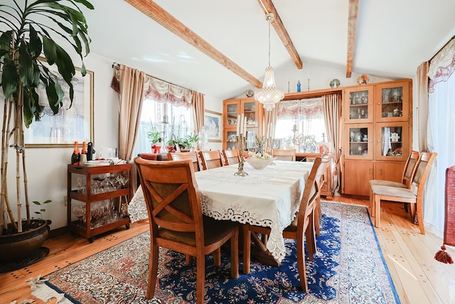 dining area featuring a notable chandelier, light hardwood / wood-style flooring, lofted ceiling with beams, and a wealth of natural light