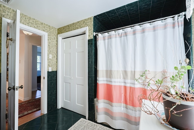 bathroom with tile walls, a shower with shower curtain, and tile patterned flooring